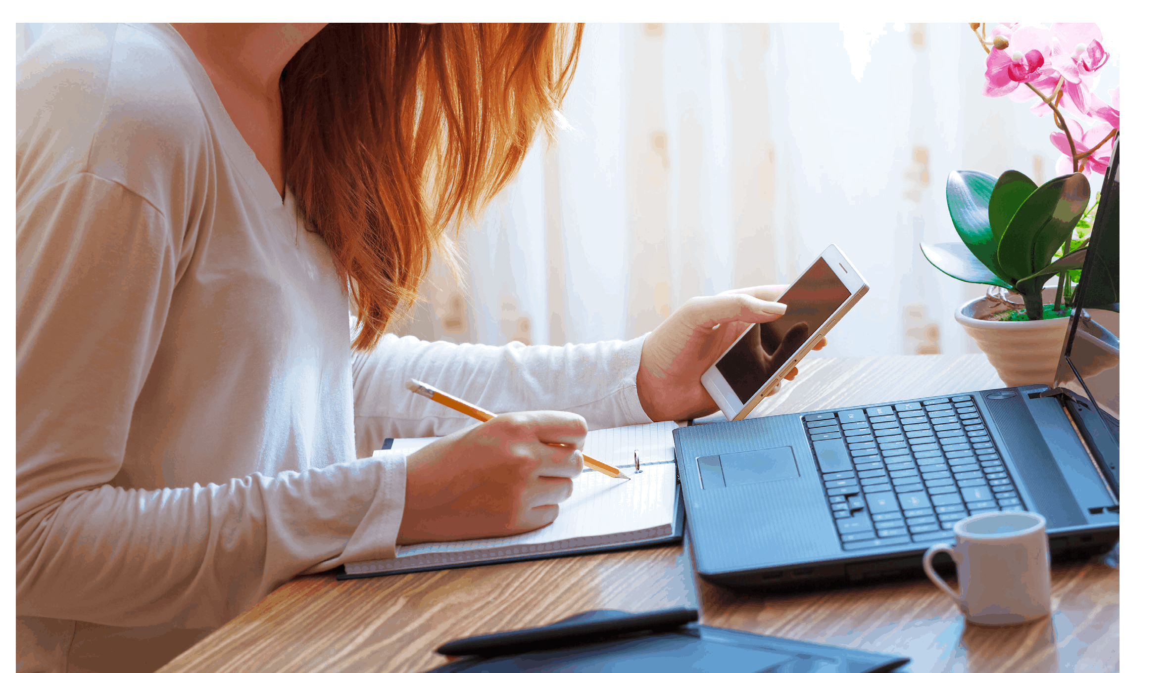 person working at her desk in a notebook and smartphone